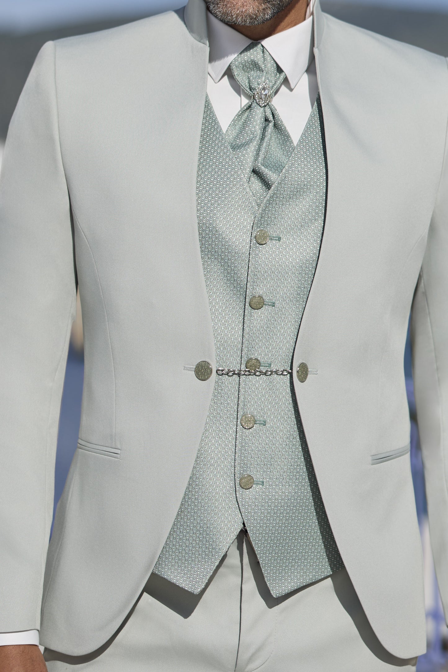 Gros plan sur le gilet 5 boutons du costume mariage vert sauge avec boutons bijoux et tissu premium