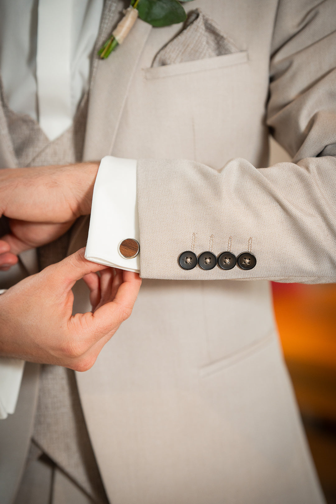 Gros plan sur les boutons de la manche du costume de marié Mathéo beige. Boutons cousus de coloris contrasté marron foncé et bouton de manchette en bois