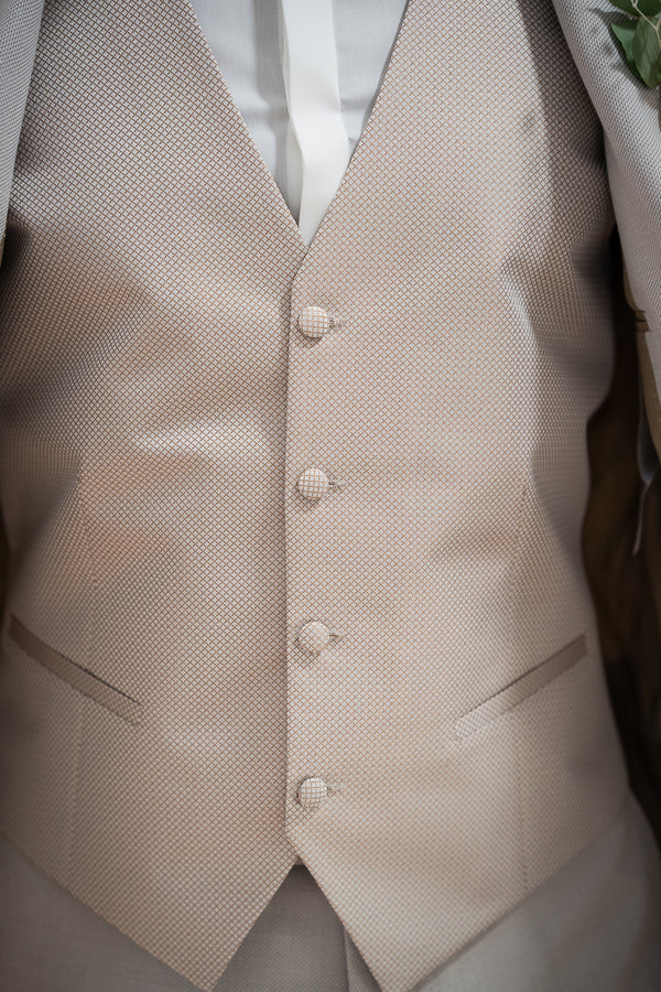 

Détail gilet beige, parfait pour un mariage ou toute autre cérémonie spéciale.  Sa texture subtile et sa couleur neutre apporteront une touche de sophistication à votre tenue.  Le tissage fin et raffiné offre un confort optimal tout au long de la journée, tandis que les boutons discrets ajoutent une note d'élégance intemporelle.  Ce gilet s'adapte à toutes les morphologies et se combine facilement avec une chemise blanche et un costume pour une allure classique et raffinée. 