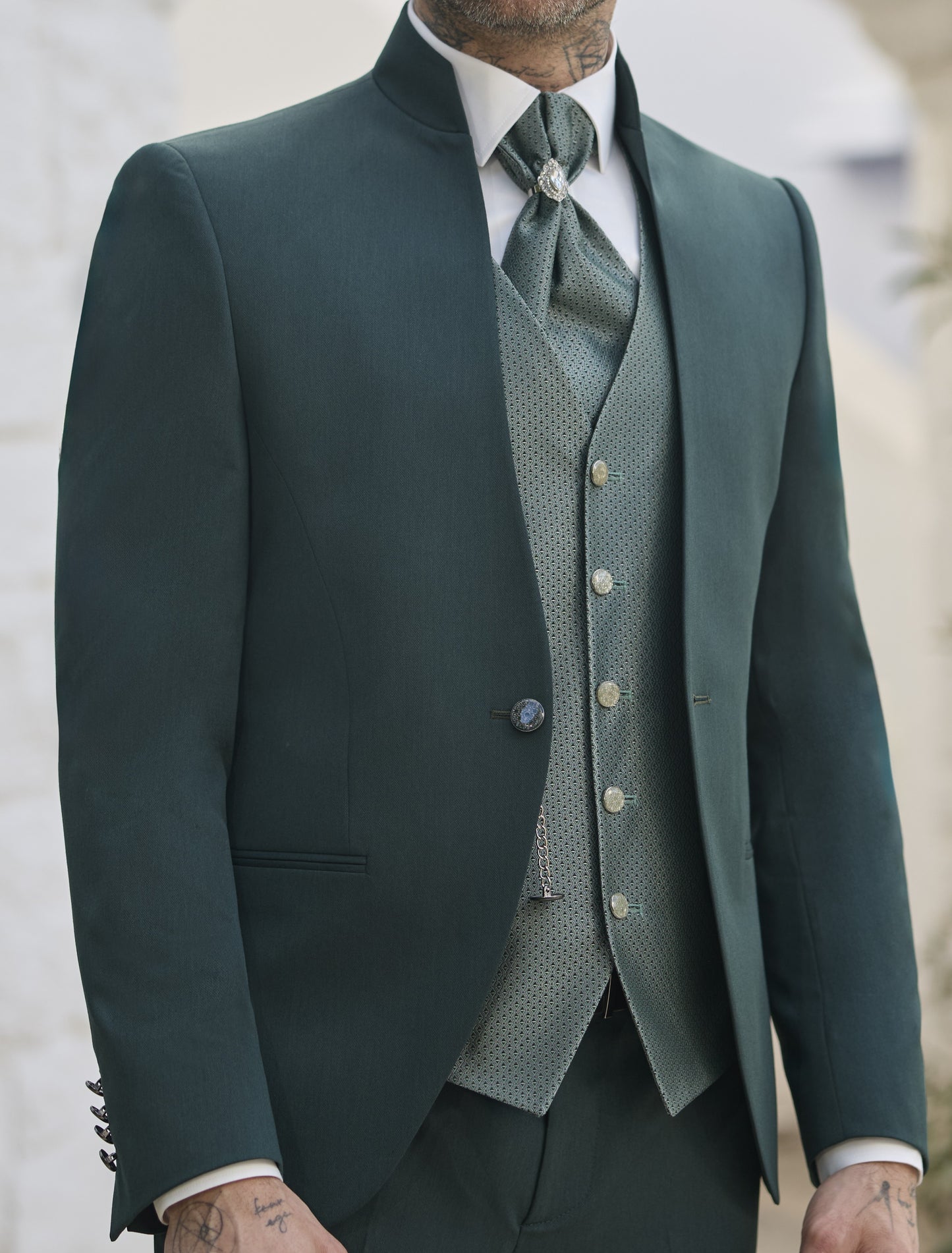 Détail costume vert sapin homme, col officier, avec gilet et lavallière à motifs.