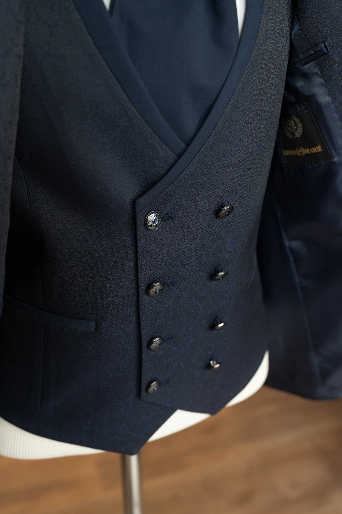 Détail du gilet croisé à double boutonnage en tissu jacquard bleu nuit avec boutons travaillés.