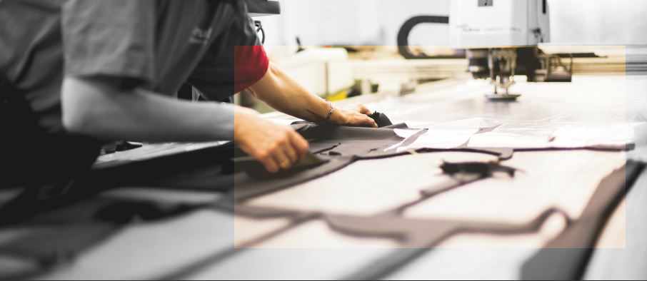 Fabrication de costumes pour homme. Une machine de coupe industrielle prépare les pièces de tissu pour des costumes de haute qualité.